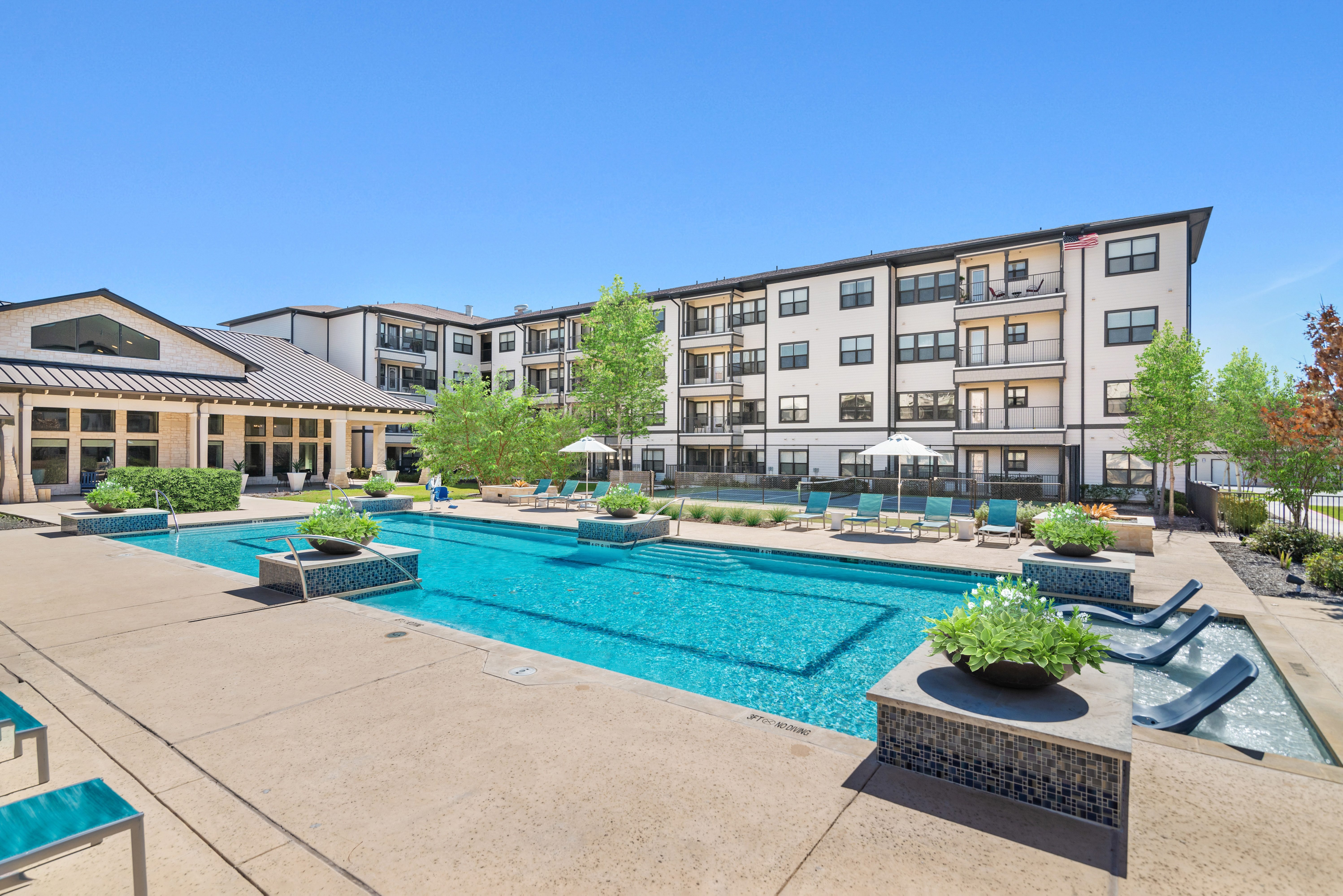 A large swimming pool surrounded by lounge chairs and potted plants.
